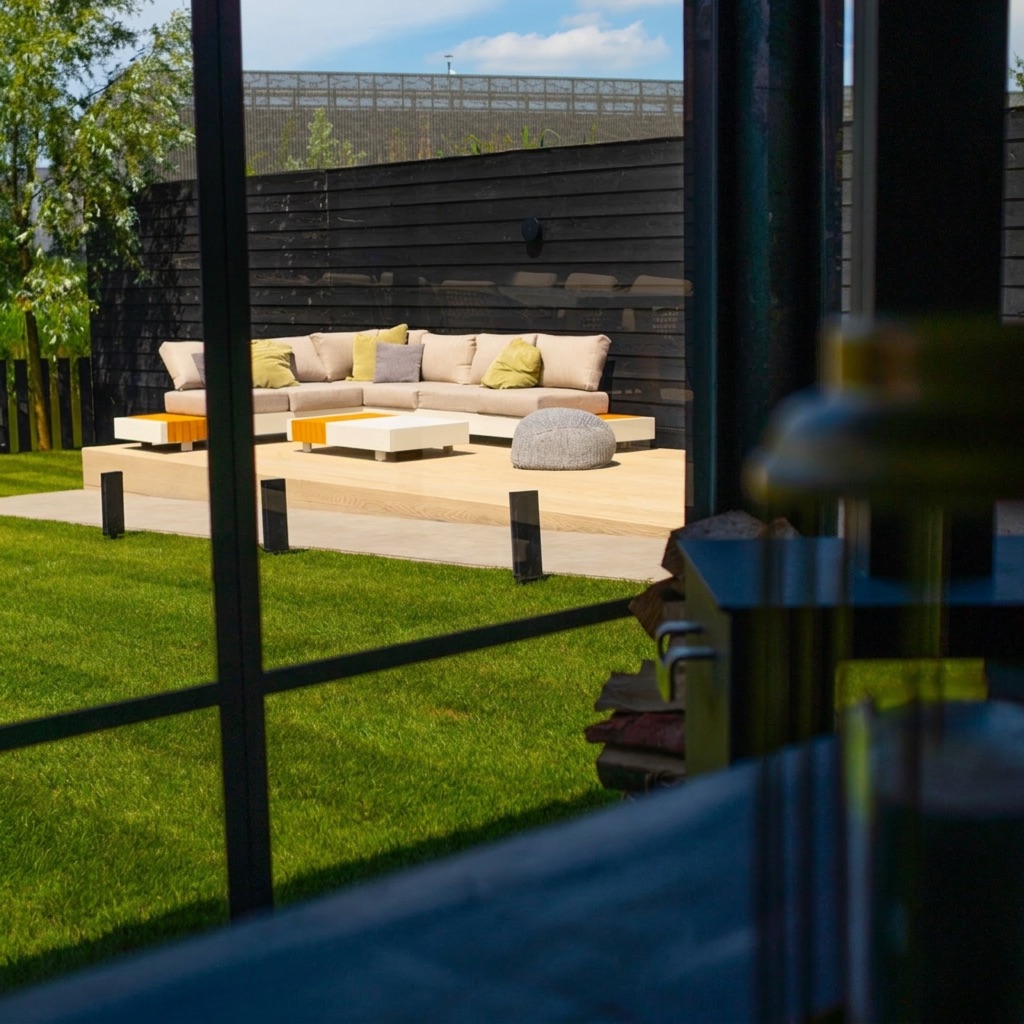 Moderne loungetuin met vlonderterras, loungeset en sfeervolle beplanting